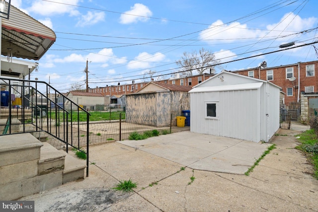 view of patio with fence, a storage unit, an outbuilding, and stairs