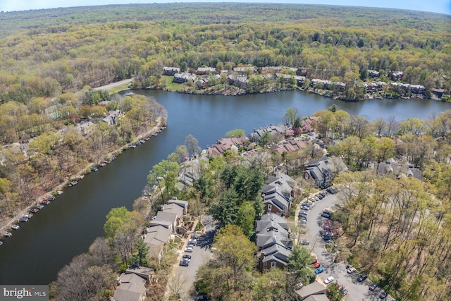 aerial view of property's location with a forest, a nearby body of water, and nearby suburban area