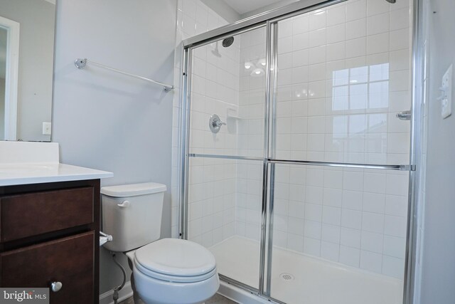full bath with a shower stall, vanity, and toilet