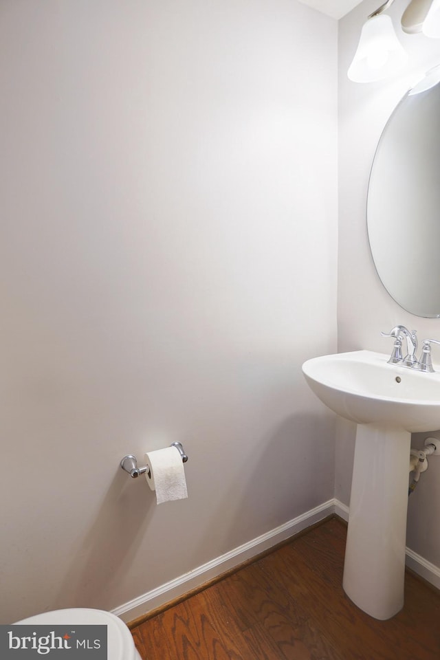 bathroom featuring baseboards, a sink, toilet, and wood finished floors