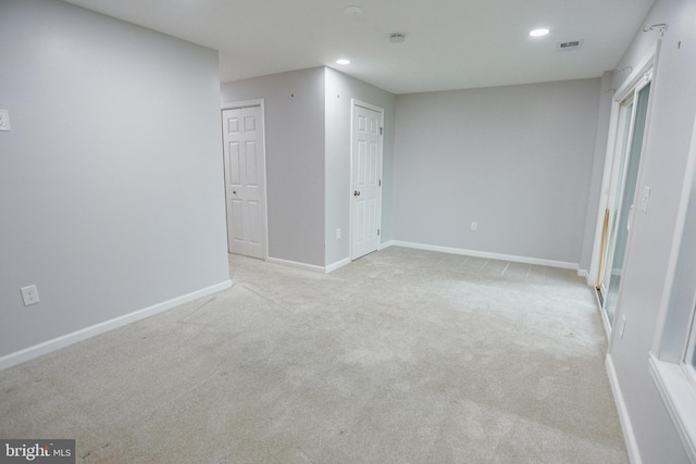 below grade area featuring visible vents, baseboards, recessed lighting, and light colored carpet