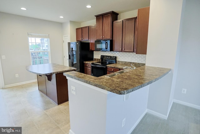 kitchen with a sink, decorative backsplash, black appliances, and a kitchen bar