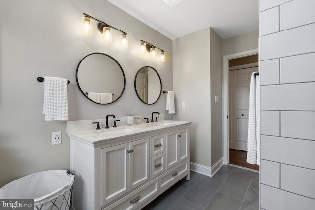 bathroom featuring double vanity, a sink, tile patterned flooring, and baseboards