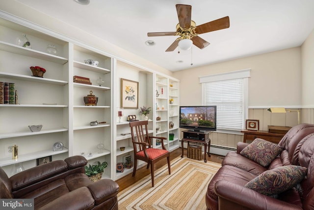 living area featuring wood finished floors, a ceiling fan, and a baseboard radiator