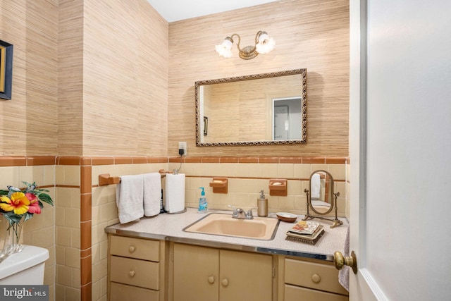 half bathroom featuring toilet, vanity, and tile walls