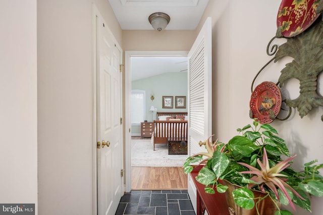 hall featuring stone finish floor and vaulted ceiling