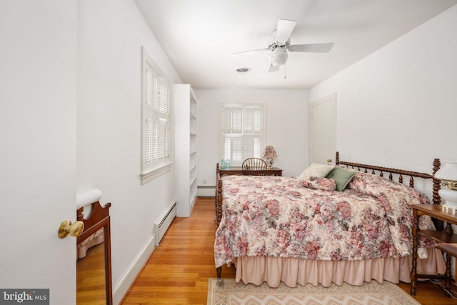 bedroom with a baseboard radiator, visible vents, light wood-style floors, and baseboards