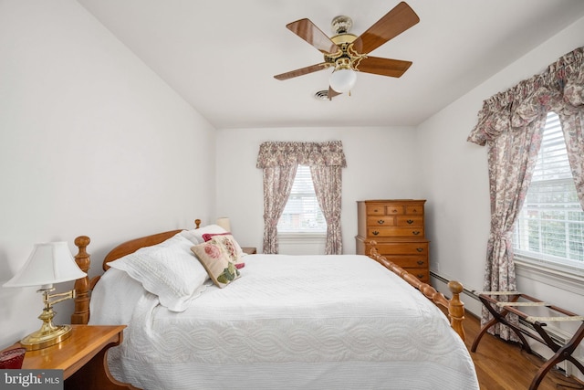 bedroom featuring a ceiling fan, visible vents, and wood finished floors