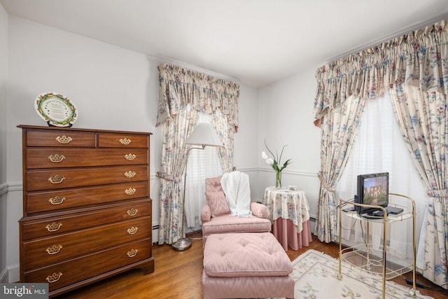 living area featuring plenty of natural light, baseboard heating, and wood finished floors