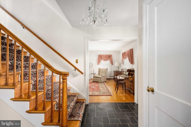 foyer entrance featuring baseboards, dark wood-style floors, an inviting chandelier, and stairway
