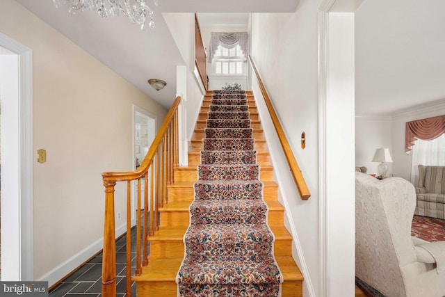 stairs with baseboards, a notable chandelier, and wood finished floors