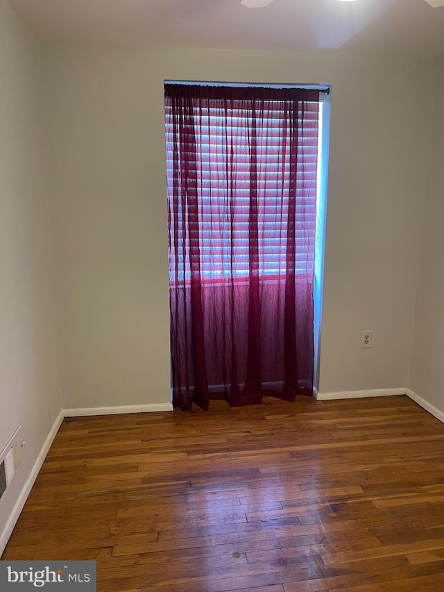 spare room featuring baseboards, visible vents, and hardwood / wood-style flooring