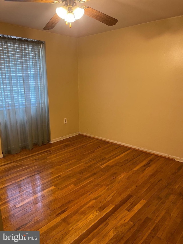 spare room with baseboards, a ceiling fan, and wood finished floors