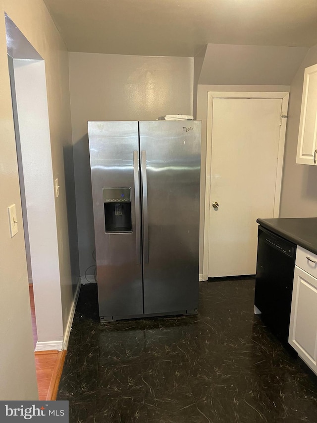 kitchen with dark countertops, stainless steel fridge, dishwasher, white cabinetry, and baseboards