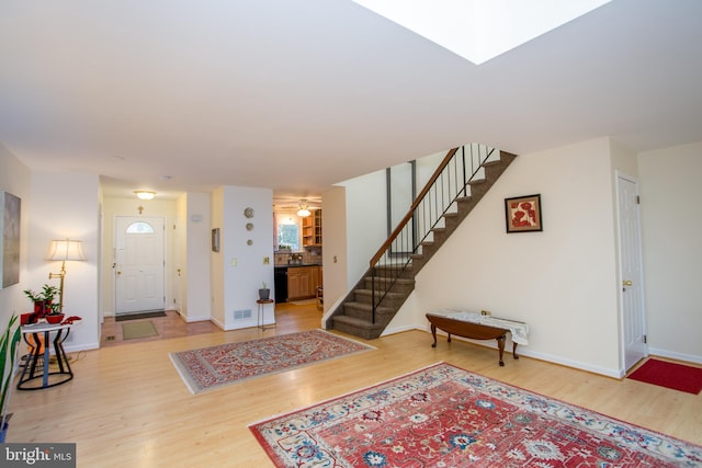 foyer entrance with wood finished floors, baseboards, visible vents, and stairway