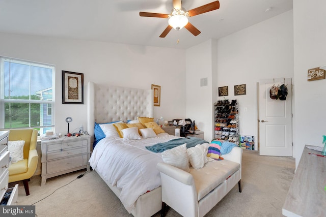 carpeted bedroom featuring high vaulted ceiling and a ceiling fan