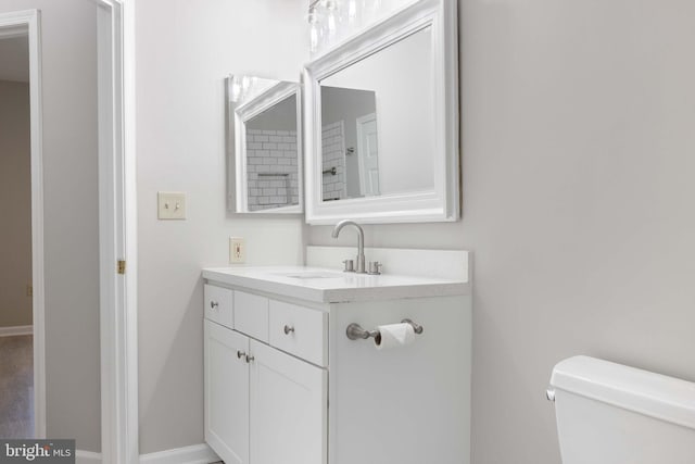 bathroom featuring vanity, baseboards, and toilet