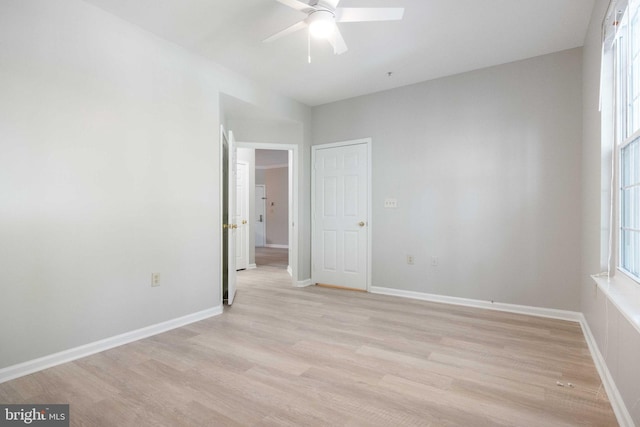 empty room with light wood-style floors, baseboards, and a ceiling fan