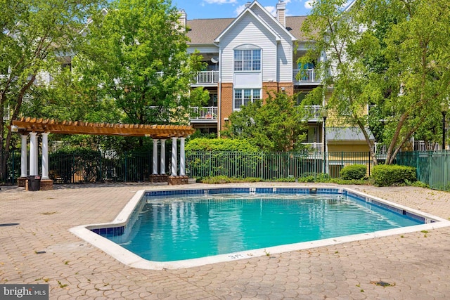 pool with a pergola, fence, and a patio