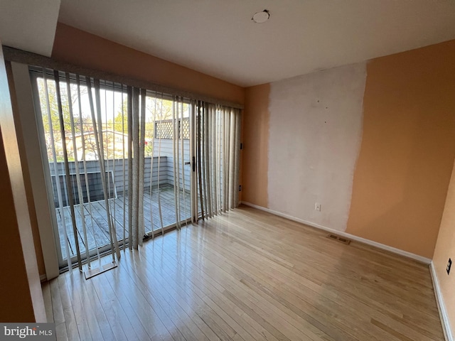 empty room with baseboards, visible vents, and wood-type flooring