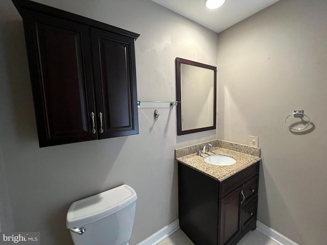 half bath with baseboards, toilet, and vanity