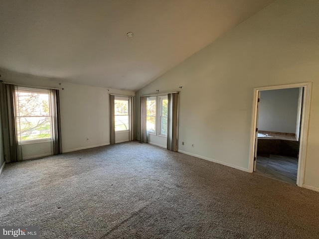 carpeted empty room featuring high vaulted ceiling and baseboards