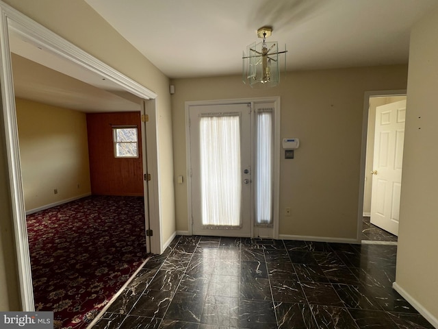 foyer featuring marble finish floor, baseboards, and an inviting chandelier