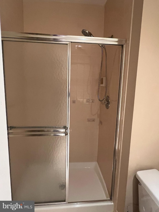 full bath with toilet and a stall shower
