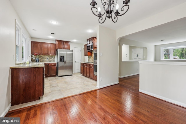 9532 Sherwood Dr, Upper Marlboro, MD 20772 - kitchen with tasteful backsplash, arched walkways, stainless steel appliances, baseboards, and light wood-type flooring