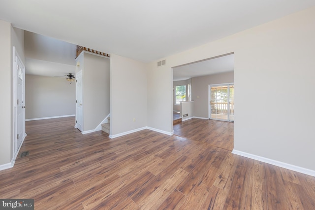 unfurnished room with baseboards, visible vents, wood finished floors, and stairway