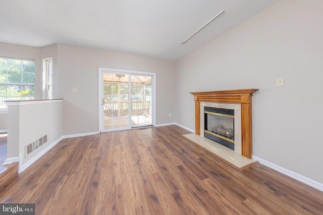unfurnished living room featuring baseboards, visible vents, a glass covered fireplace, and wood finished floors