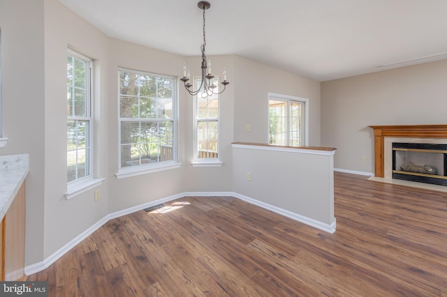 unfurnished dining area featuring dark wood-style flooring, an inviting chandelier, a healthy amount of sunlight, and visible vents