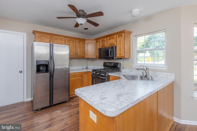 kitchen featuring a sink, stainless steel fridge with ice dispenser, black range with gas stovetop, light countertops, and a peninsula