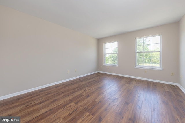 spare room with baseboards and dark wood finished floors