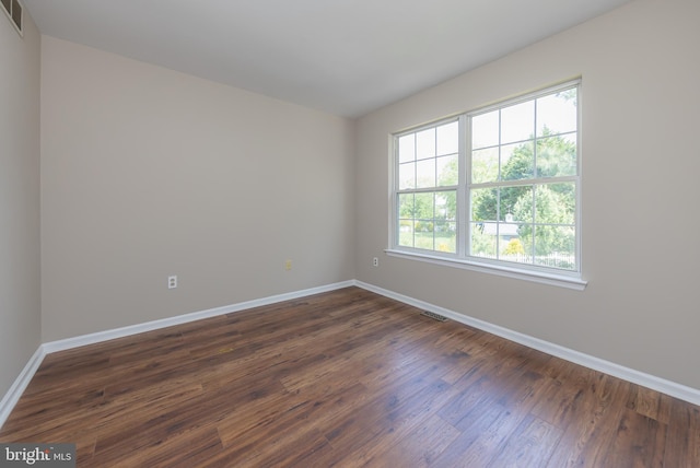 empty room with baseboards, dark wood finished floors, and visible vents