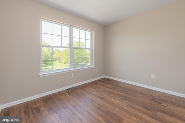 empty room featuring visible vents, baseboards, and dark wood-type flooring