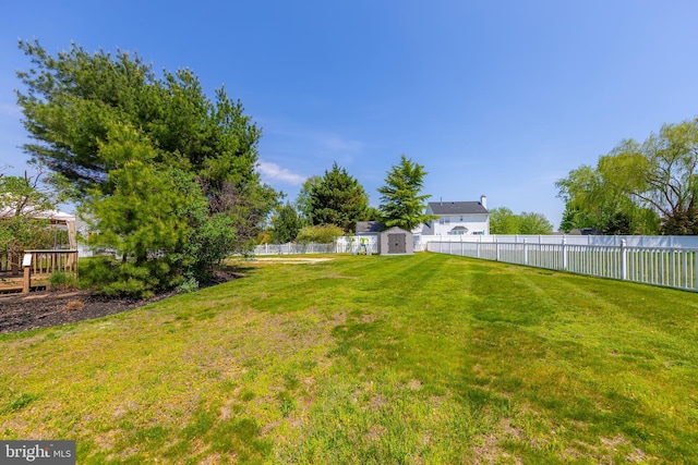 view of yard with a storage shed, an outbuilding, and a fenced backyard