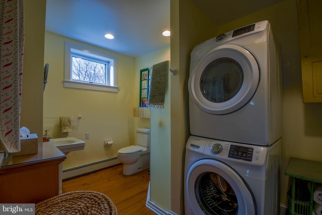 laundry room with laundry area, recessed lighting, wood finished floors, a baseboard radiator, and stacked washer and clothes dryer