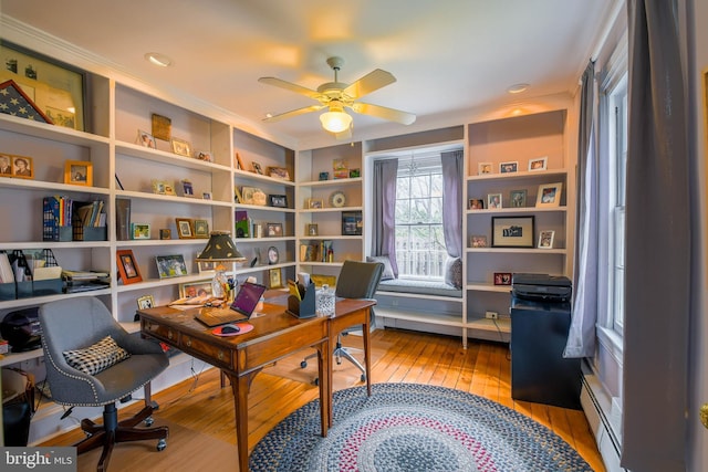 office space with light wood finished floors, a ceiling fan, a baseboard radiator, and ornamental molding