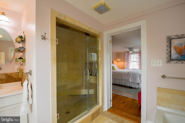 ensuite bathroom featuring connected bathroom, ceiling fan, vanity, and a stall shower