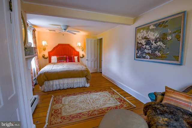 bedroom with a baseboard heating unit, baseboards, a ceiling fan, and wood finished floors