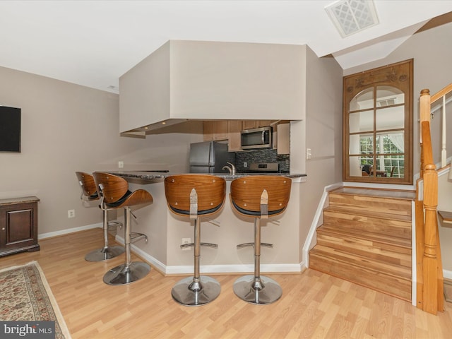 353 Fallsgrove Dr Unit 51, Rockville, MD 20850 - kitchen with stainless steel microwave, backsplash, light wood-style floors, visible vents, and freestanding refrigerator