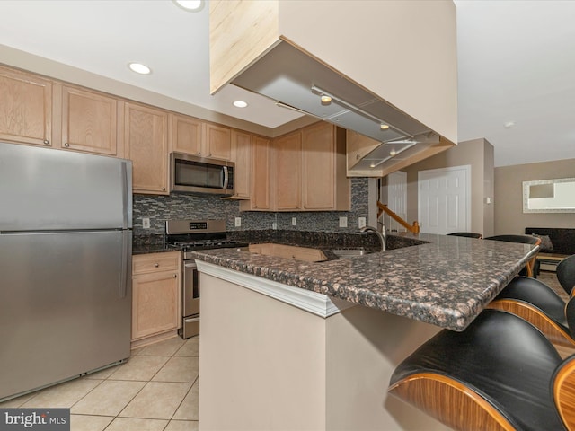 353 Fallsgrove Dr Unit 51, Rockville, MD 20850 - kitchen featuring light tile patterned flooring, backsplash, a kitchen breakfast bar, light brown cabinetry, and stainless steel appliances