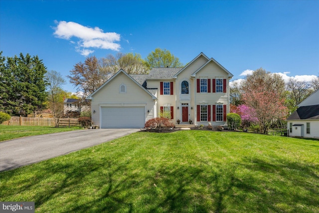 traditional home featuring a front lawn, driveway, an attached garage, and fence