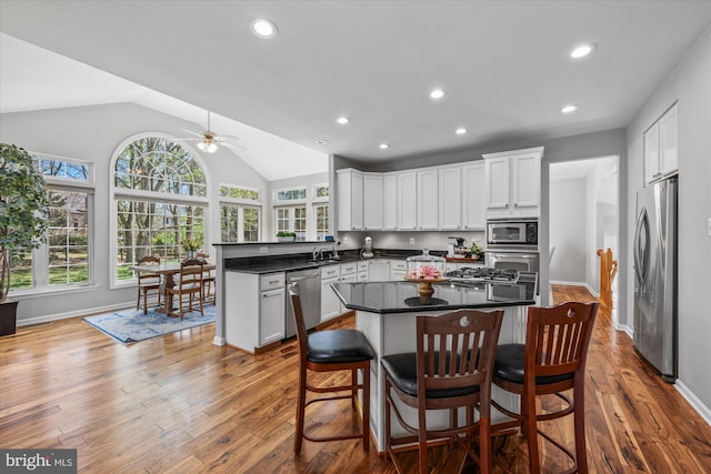 kitchen with a sink, stainless steel appliances, a ceiling fan, a peninsula, and lofted ceiling