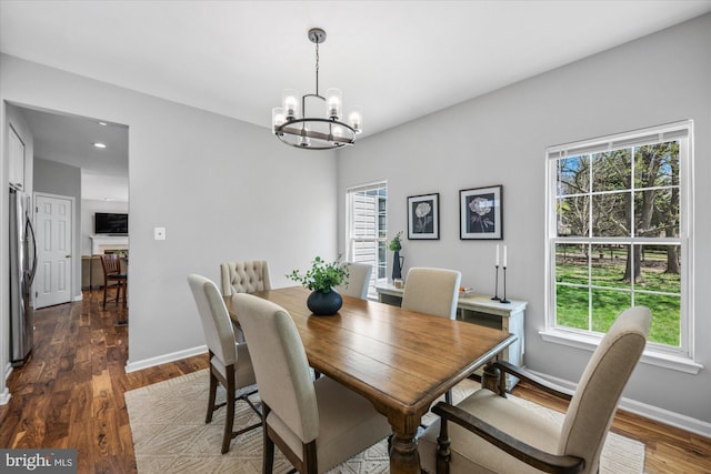 dining area featuring dark wood finished floors, an inviting chandelier, baseboards, and a healthy amount of sunlight