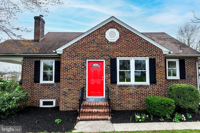 view of front of house with brick siding, a shingled roof, and a chimney