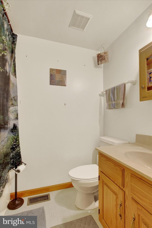 bathroom featuring vanity, toilet, tile patterned floors, and baseboards
