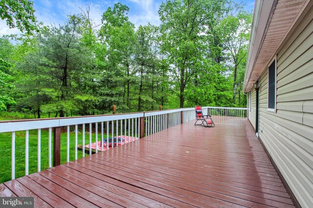wooden deck featuring a lawn and view of scattered trees