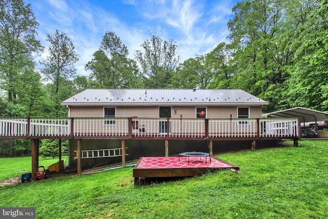 rear view of property with a deck, metal roof, a yard, and a carport